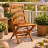 A Twisted Papasan Chair (Clearance) sits on an outdoor deck, surrounded by string lights, potted plants, and a small table with wine glasses and grapes.