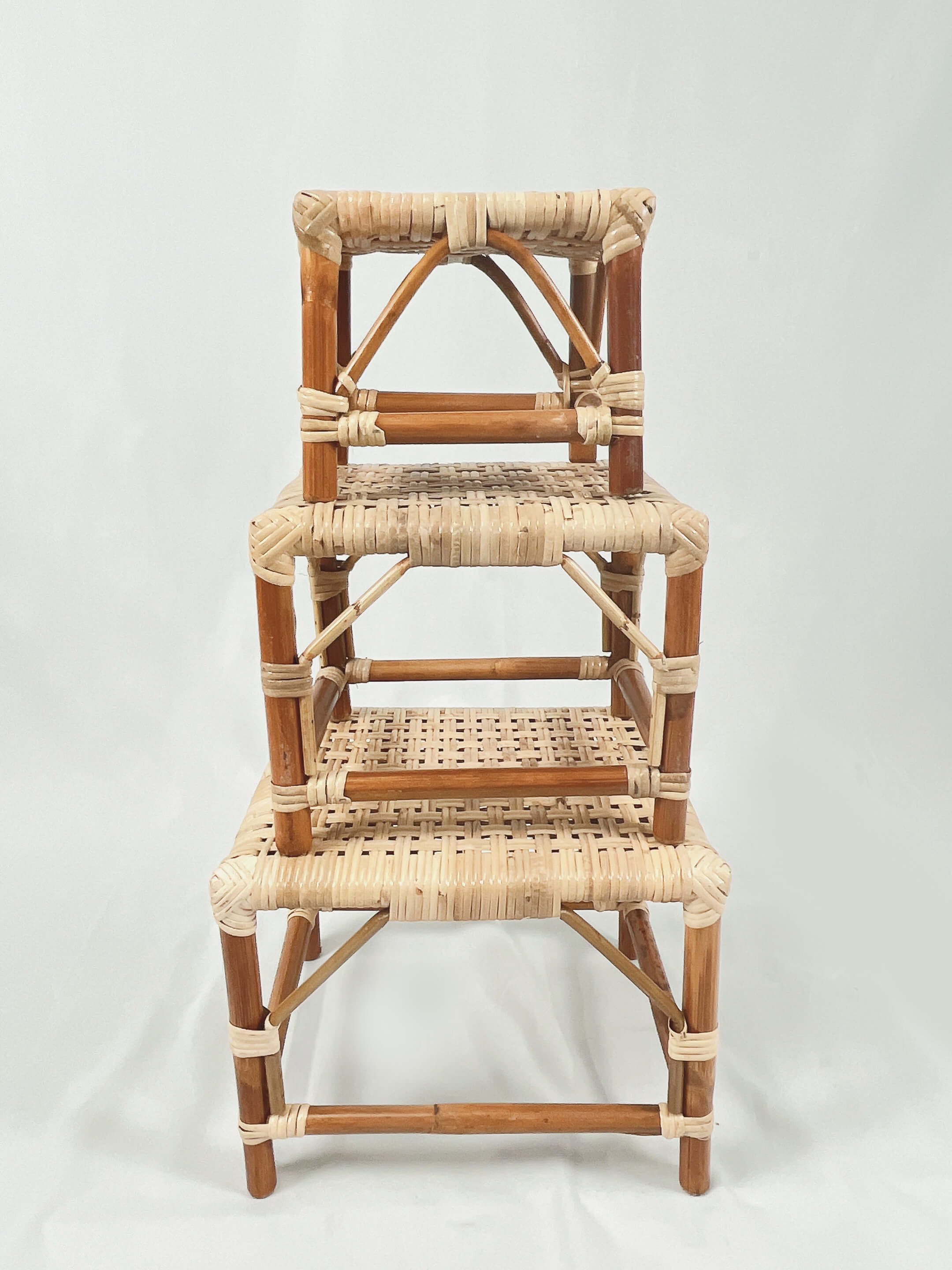 Three stacked rattan stools of decreasing size on a plain white background.
