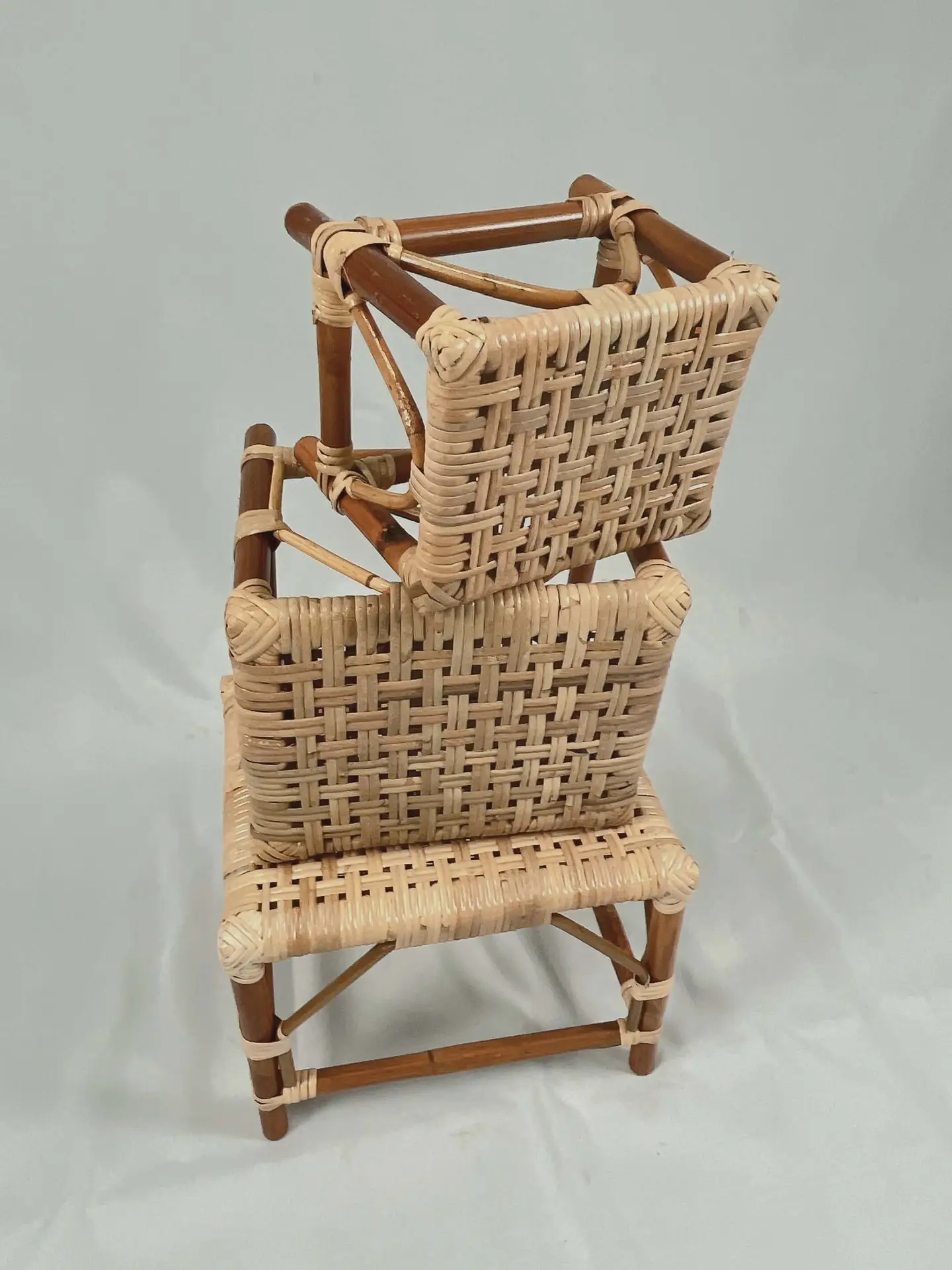 Two RC Sewing Stools made of wicker and wood are stacked one on top of the other against a plain background.