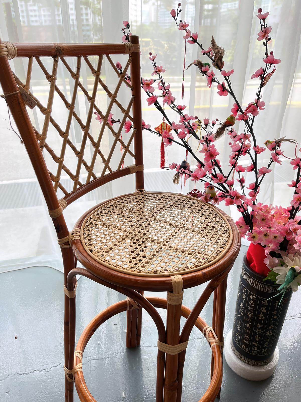 A PO - RC Bar Stool (With Backframe) is placed next to a decorative vase with pink flowers and hanging ornaments.