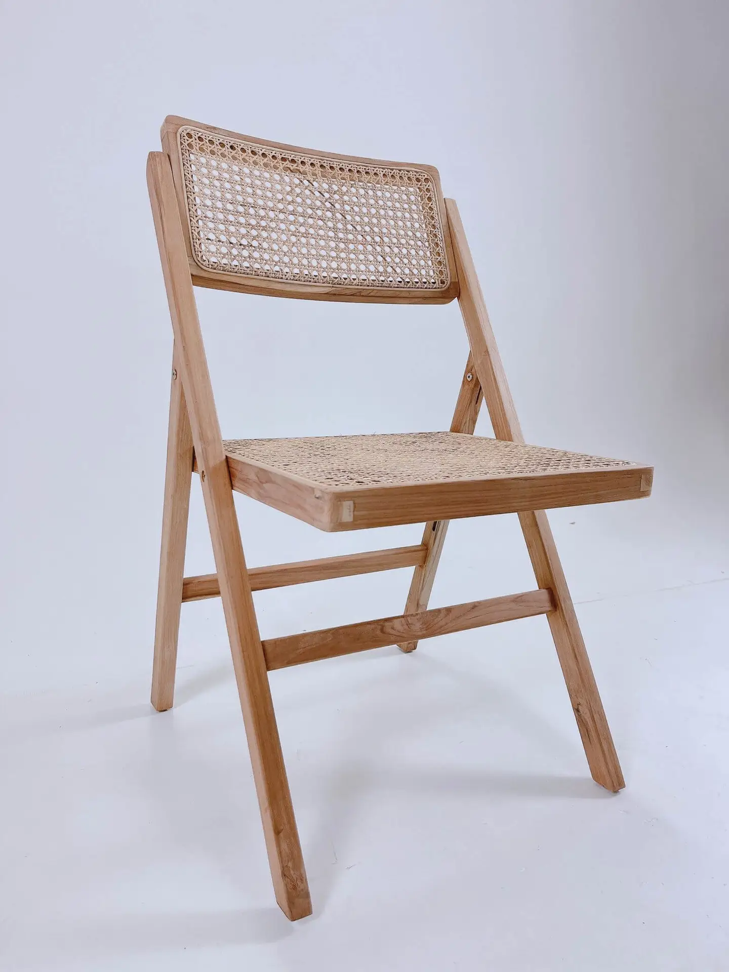 A light wood folding chair with a cane woven seat and backrest on a plain white background.