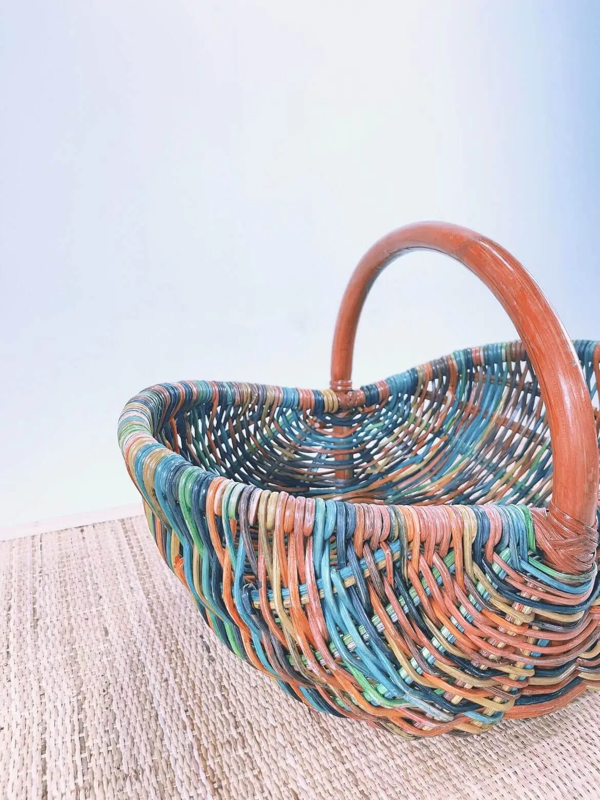 Dawn's Plant Pot, adorned with vibrant patterns and featuring a wooden handle, sits on a textured surface against a light blue background.