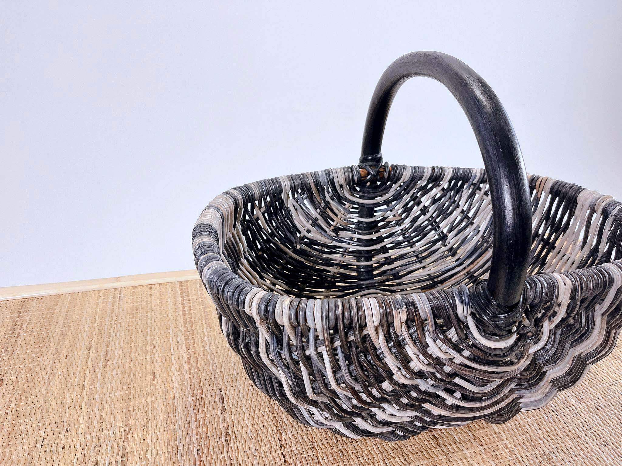 A Wicker Basket LK10 featuring a sturdy black handle sits on a woven mat against a plain background.