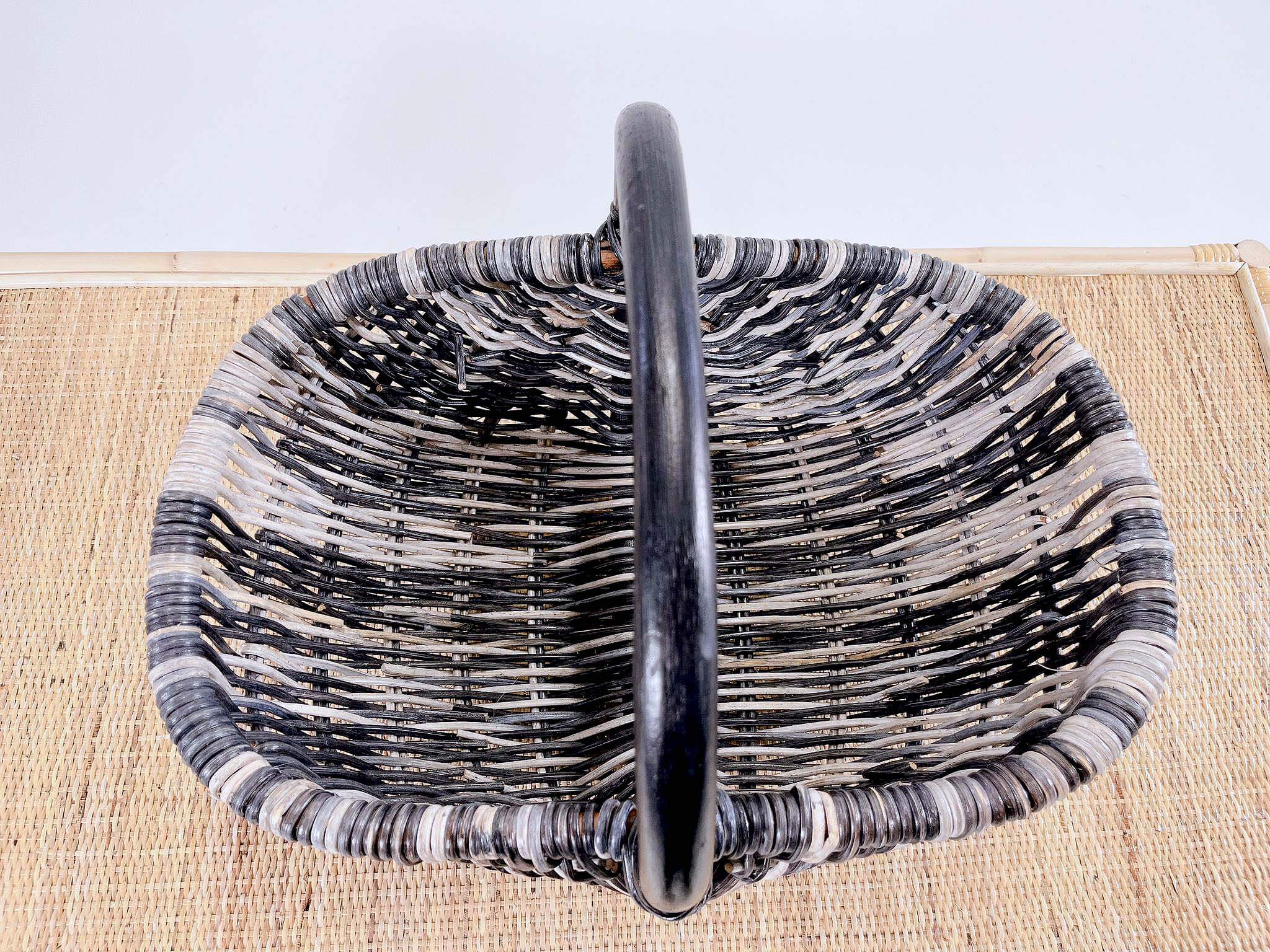 A Wicker Basket LK10 with a central handle placed on a beige woven mat.