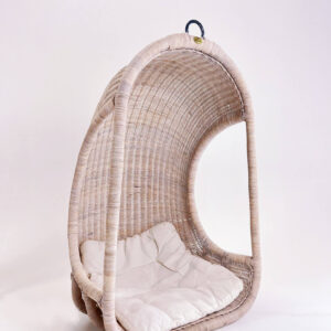A hanging wicker chair with a light cushion inside, set against a plain white background.