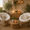 A cozy balcony featuring two Manau Papasan chairs with natural frames and cushions, a low table, potted plants, candles, and warm ambient lighting in an earthy setting.