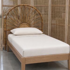 A single bed featuring the Floral Natural Rattan Headboard (Clearance) and a light wood frame is positioned in front of a woven room divider on a polished concrete floor.
