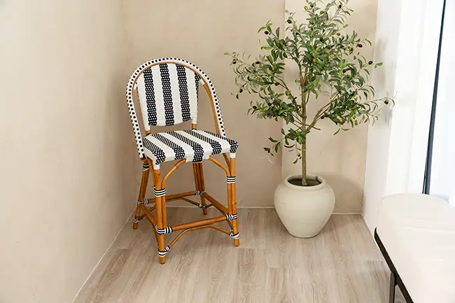 A corner with a Designer Bar Stool featuring black and white stripes next to a potted plant on a light wood floor. A corner with a Designer Bar Stool featuring black and white stripes next to a potted plant on a light wood floor.
