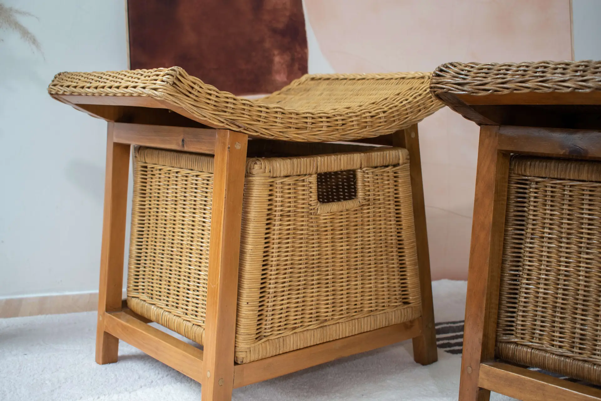 The Rattan Wicker Storage Stool combines a wicker storage basket within a wooden frame and features a woven seat on top, making it a practical seating solution and storage unit for use on a carpeted floor.