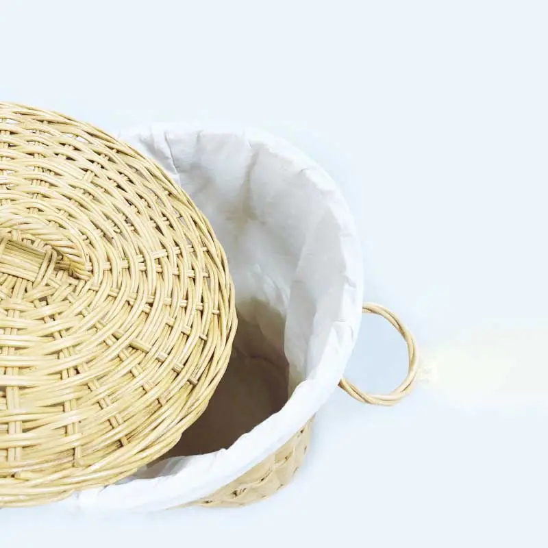 A Wicker Laundry Basket with a white liner and a partially open lid, revealing the empty interior. The basket features a handle loop on the side.