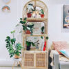 A Bookshelf With Cabinet, adorned with potted plants, books, framed photos, and decor, stands next to a light gray sofa in a bright modern living room. A Bookshelf With Cabinet, adorned with potted plants, books, framed photos, and decor, stands next to a light gray sofa in a bright modern living room.