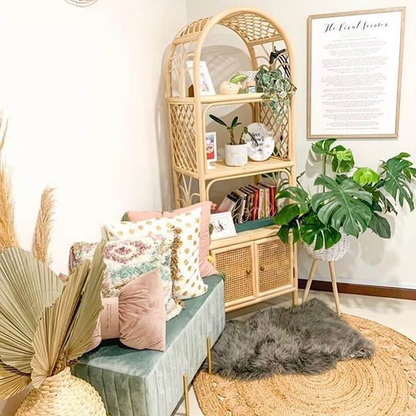 A cozy corner features a green bench with colorful pillows, a Bookshelf With Cabinet holding plants and books, a framed print on the wall, and decorative baskets on a circular rug. A cozy corner features a green bench with colorful pillows, a Bookshelf With Cabinet holding plants and books, a framed print on the wall, and decorative baskets on a circular rug.