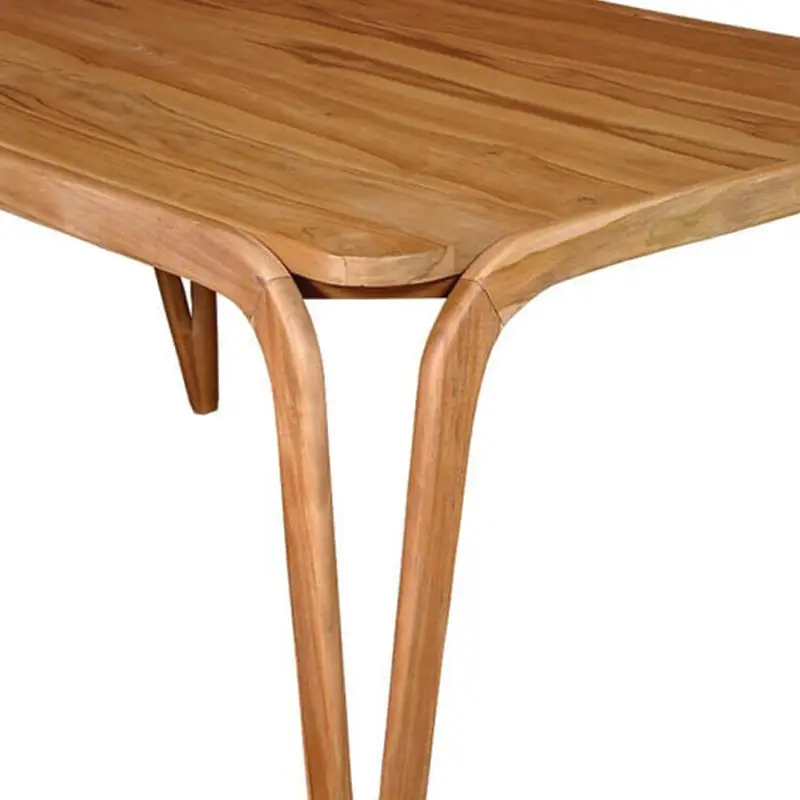 The Trombone V Dining Table is a wooden table with curved legs and a smooth rectangular tabletop, featuring a natural wood grain finish.