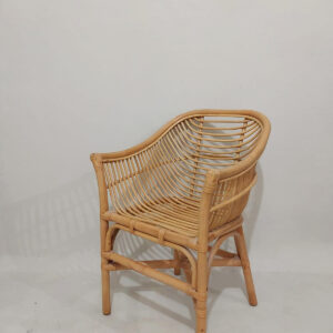 The Lazio Core Chair, featuring curved armrests, a woven backrest and seat, and a white seat cushion, sits on a light-colored floor against a white wall.