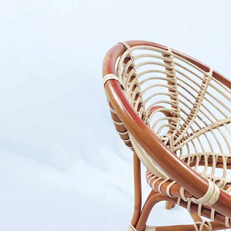A close-up view of the RC Coil Hami Chair 20", showcasing its round, woven rattan design with curved lines and natural color, set against a plain white background.