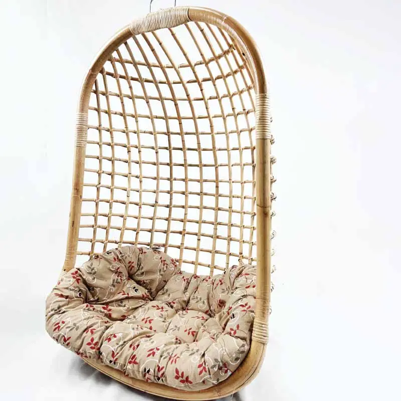 The Rattan Swing With Seat Cushion is a wooden hanging chair with a woven frame, featuring a cushioned seat draped in beige fabric adorned with red floral patterns.